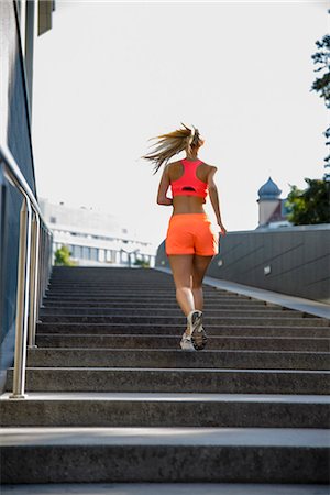 exuberant woman in sunlight - Young female runner moving up city stairway Stock Photo - Premium Royalty-Free, Code: 649-07559763