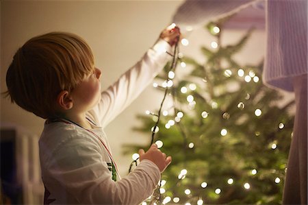 festa di natale - Young boy putting up christmas tree lights Fotografie stock - Premium Royalty-Free, Codice: 649-07559802