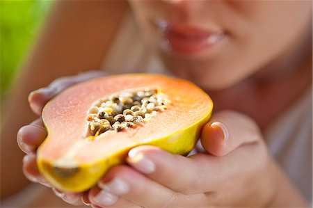 Woman holding up halved papaya Stock Photo - Premium Royalty-Free, Code: 649-07559811