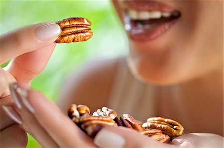 finger in mouth - Woman with handful of pecans Photographie de stock - Premium Libres de Droits, Code: 649-07559813