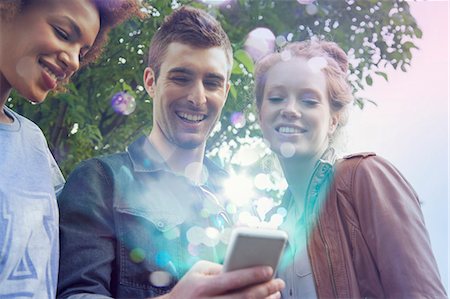 smartphone outdoors - Three friends looking at smartphone with lights coming out of it Stock Photo - Premium Royalty-Free, Code: 649-07560139