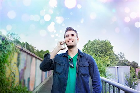 Young man talking on smartphone with glowing lights above Stock Photo - Premium Royalty-Free, Code: 649-07560147