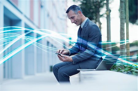 Waves of blue light and businessman texting on smartphone Stock Photo - Premium Royalty-Free, Code: 649-07560155