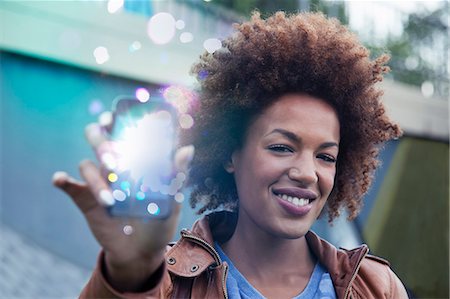 futuristic technology ideas - Young woman holding up smartphone with glowing lights coming out Stock Photo - Premium Royalty-Free, Code: 649-07560151