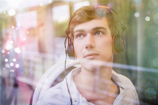 Young man on train, daydreaming and listening to headphones Stock Photo - Premium Royalty-Free, Image code: 649-07560167