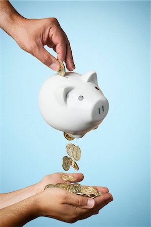 Hand putting coin into piggy bank and coins flowing out Stock Photo - Premium Royalty-Free, Code: 649-07560259