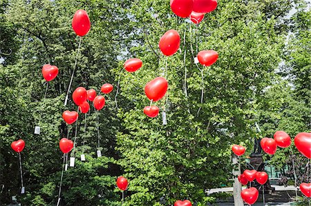 red baloons - Red heart shaped balloons floating upward from park Stock Photo - Premium Royalty-Free, Code: 649-07560397