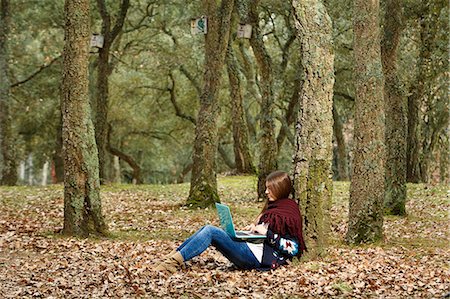 Young woman using laptop in forest Stock Photo - Premium Royalty-Free, Code: 649-07560402