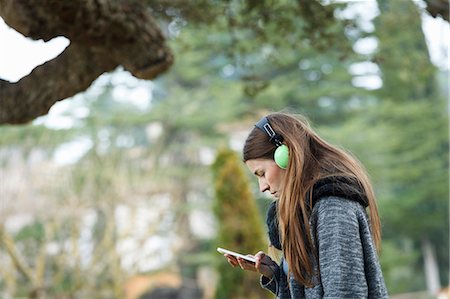 Young woman using mp3 in forest Stock Photo - Premium Royalty-Free, Code: 649-07560419