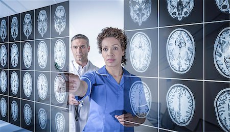 Doctor and nurse working with MRI brain scans seen through interactive display Stock Photo - Premium Royalty-Free, Code: 649-07560483