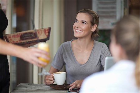 Two young adult female friends ordering from menu in cafe Foto de stock - Sin royalties Premium, Código: 649-07585059