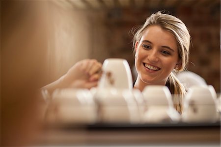 people picking coffee - Young female waitress picking up cup from tray in cafe Stock Photo - Premium Royalty-Free, Code: 649-07585066