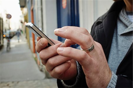 Mid adult man on sidewalk using touchscreen on smartphone Photographie de stock - Premium Libres de Droits, Code: 649-07585108