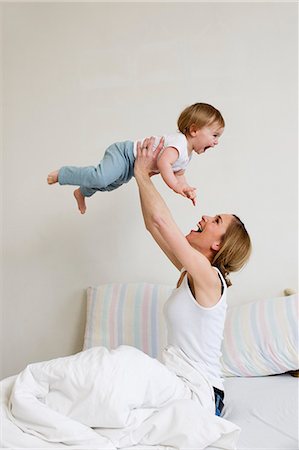 Portrait of mid adult woman holding up her one year old baby girl Stock Photo - Premium Royalty-Free, Code: 649-07585436