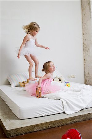 Two young sisters dressed as ballet dancers playing on bed Foto de stock - Sin royalties Premium, Código: 649-07585444