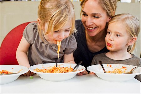 people eating on the table - Mid adult mother eating spaghetti with her two young daughters Foto de stock - Sin royalties Premium, Código: 649-07585475