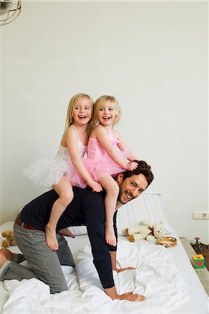 family playing indoor - Portrait of mid adult father giving two young daughters a piggy back Stock Photo - Premium Royalty-Free, Code: 649-07585478