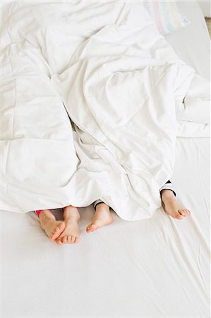 Young sisters feet sticking out of duvet on bed Fotografie stock - Premium Royalty-Free, Codice: 649-07585470