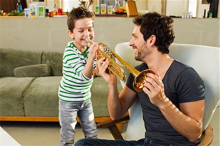 photo of happy family stand front of home - Father encouraging young son playing trumpet Stock Photo - Premium Royalty-Free, Code: 649-07585484