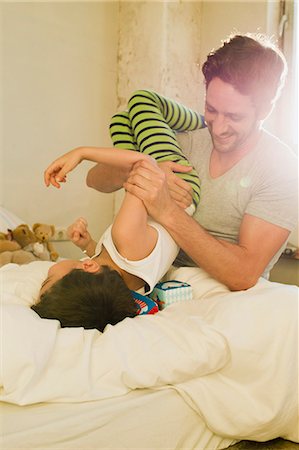 parent holding child upside down - Father and young son play fighting on bed Stock Photo - Premium Royalty-Free, Code: 649-07585488