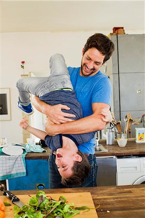 Father holding young son upside down in kitchen Foto de stock - Sin royalties Premium, Código: 649-07585483