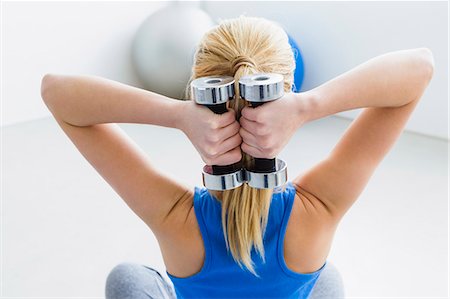 physical fitness - Young woman lifting weights, rear view Stock Photo - Premium Royalty-Free, Code: 649-07585519