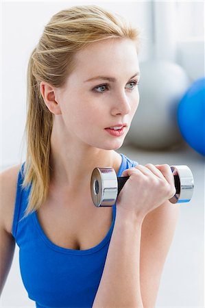 dumb bell in a gym - Young woman lifting weights Stock Photo - Premium Royalty-Free, Code: 649-07585521