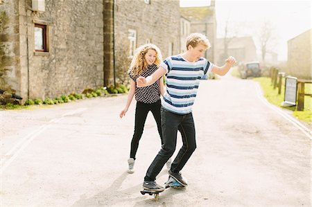 Teenage brother and sister skateboarding on rural road Stock Photo - Premium Royalty-Free, Code: 649-07585754
