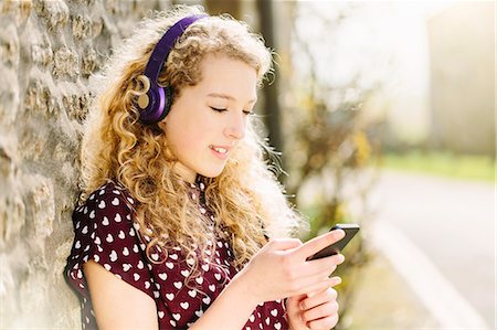 spotted (pattern) - Portrait of teenage girl in village with headphones and smartphone Stock Photo - Premium Royalty-Free, Code: 649-07585757