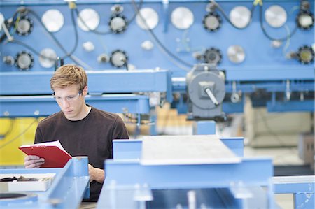 electronics - Mid adult male technician checking paperwork in engineering plant Stock Photo - Premium Royalty-Free, Code: 649-07585775
