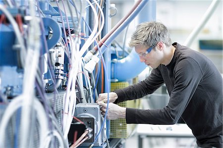 Mid adult male technician maintaining cables in engineering plant Photographie de stock - Premium Libres de Droits, Code: 649-07585773
