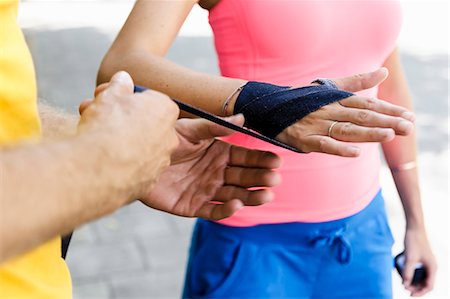 Personal trainer wrapping bandages around female boxers hand Stock Photo - Premium Royalty-Free, Code: 649-07596114