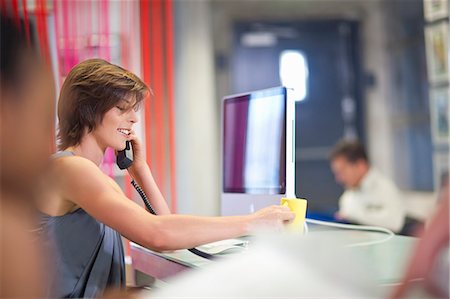 Young businesswoman using telephone in office Stock Photo - Premium Royalty-Free, Code: 649-07596176