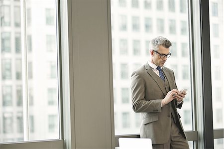 entrepreneur (male) - Businessman texting on smartphone in office Stock Photo - Premium Royalty-Free, Code: 649-07596256