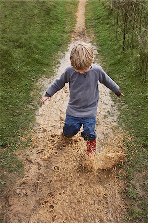 Boy splashing through muddy puddle Photographie de stock - Premium Libres de Droits, Code: 649-07596306