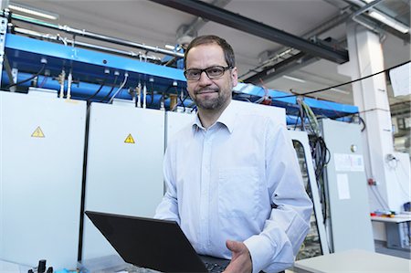 Portrait of manager holding laptop in workshop Stock Photo - Premium Royalty-Free, Code: 649-07596564