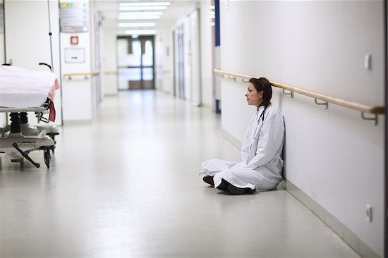 Female doctor sitting cross legged in hospital corridor Stock Photo - Premium Royalty-Free, Image code: 649-07596573