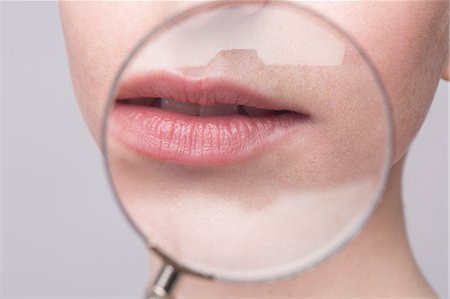 Portrait of young woman, magnifying glass on mouth Photographie de stock - Premium Libres de Droits, Code: 649-07647878