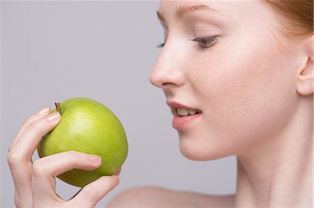 Portrait of young woman, holding green apple Stock Photo - Premium Royalty-Free, Code: 649-07647880