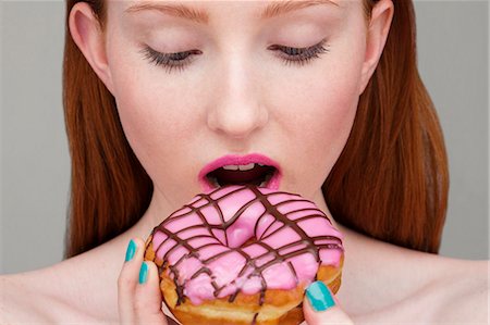 simsearch:6122-07697627,k - Young woman biting donut Stock Photo - Premium Royalty-Free, Code: 649-07647903