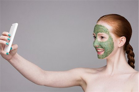 simsearch:614-06442320,k - Young woman wearing face mask, taking self portrait photograph with smartphone Stock Photo - Premium Royalty-Free, Code: 649-07647911