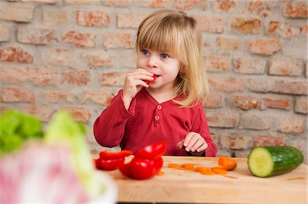 Two year old girl in kitchen eating raw vegetables Stock Photo - Premium Royalty-Free, Code: 649-07647970