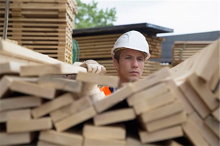 Portrait of young male worker behind wood planks in timber yard Stock Photo - Premium Royalty-Free, Code: 649-07648215