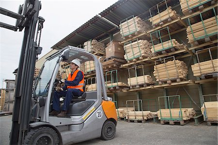 Young man driving a forklift truck in timber yard Foto de stock - Sin royalties Premium, Código: 649-07648213