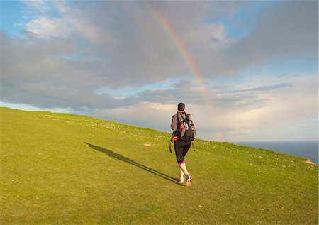 east sussex - Young female hiker, hiking up hill toward rainbow Photographie de stock - Premium Libres de Droits, Code: 649-07648258