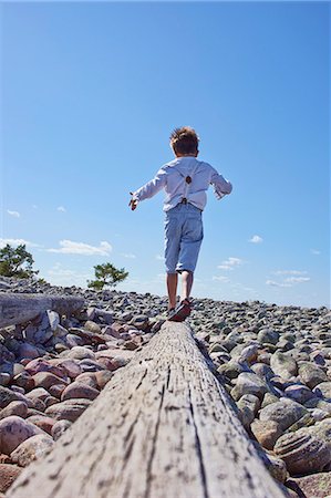 Boy balancing on log on beach Foto de stock - Sin royalties Premium, Código: 649-07648396