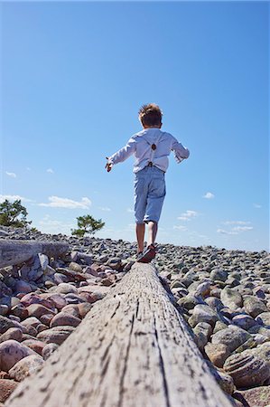 simsearch:649-07648395,k - Boy balancing on log on beach Photographie de stock - Premium Libres de Droits, Code: 649-07648396