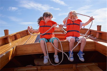 Two children sitting in boat, holding rope Stock Photo - Premium Royalty-Free, Code: 649-07648400