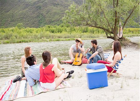 Friends sitting by river, playing guitar Stock Photo - Premium Royalty-Free, Code: 649-07648547