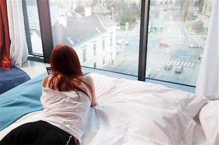 simsearch:649-07648646,k - Young woman in hotel room overlooking street Fotografie stock - Premium Royalty-Free, Codice: 649-07648646